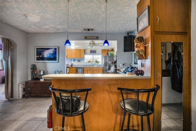 kitchen with a breakfast bar, dishwasher, kitchen peninsula, and a textured ceiling