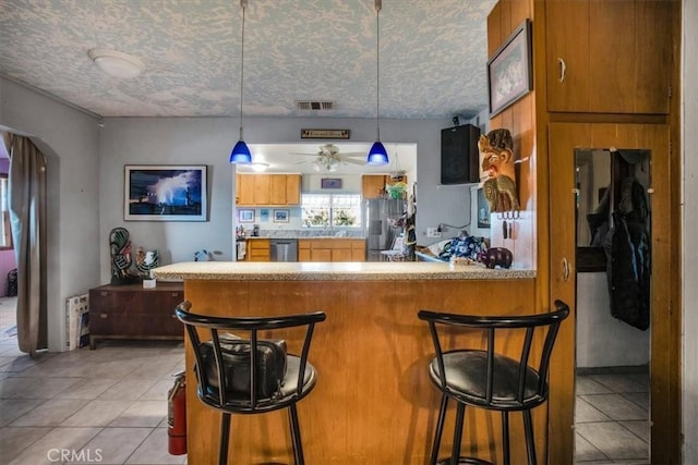 5975 Desert Star Rd Unit 1-2, Johnson Valley, CA 92285 - kitchen with visible vents, appliances with stainless steel finishes, brown cabinets, and light tile patterned flooring