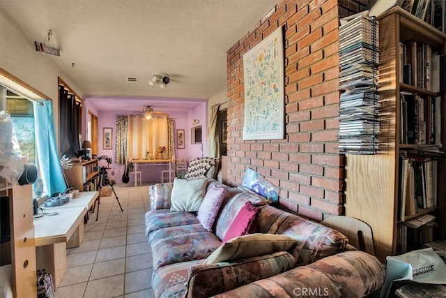 tiled living room featuring ceiling fan and brick wall