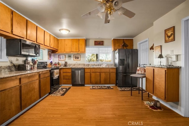 kitchen with ceiling fan, sink, appliances with stainless steel finishes, and light hardwood / wood-style floors