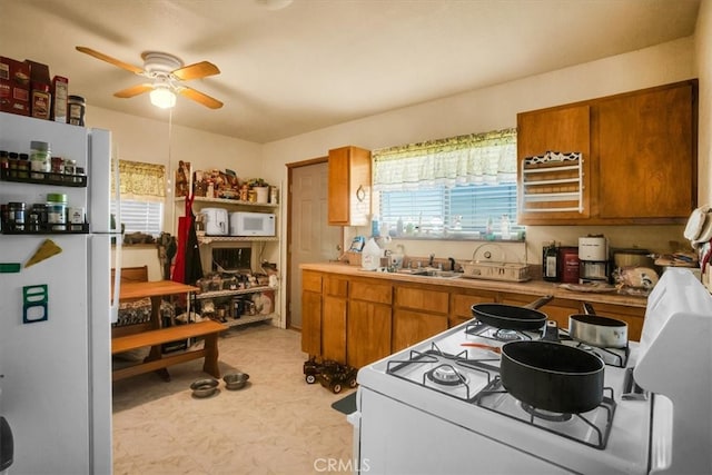 kitchen with white appliances, sink, and ceiling fan