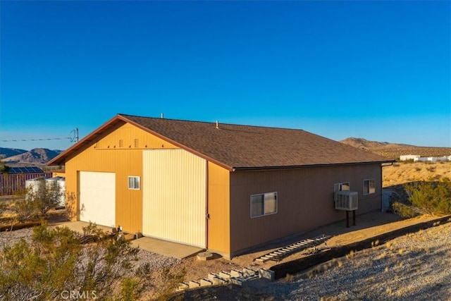 view of side of property featuring a mountain view, an outdoor structure, and a garage