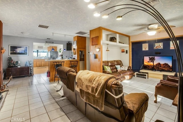 tiled living room featuring ceiling fan and a textured ceiling