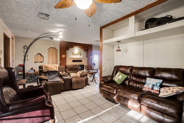 living room featuring a textured ceiling, ceiling fan, and light tile patterned floors