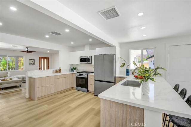 kitchen featuring stainless steel appliances, kitchen peninsula, a healthy amount of sunlight, and a breakfast bar