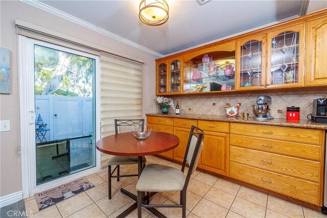 kitchen with backsplash, light stone counters, light tile patterned flooring, and ornamental molding