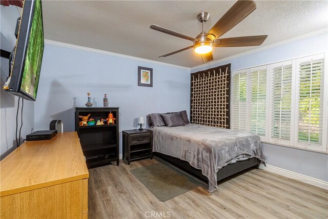 bedroom with hardwood / wood-style flooring, ceiling fan, ornamental molding, and a textured ceiling