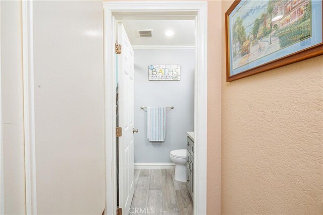 bathroom with hardwood / wood-style floors, vanity, toilet, and crown molding