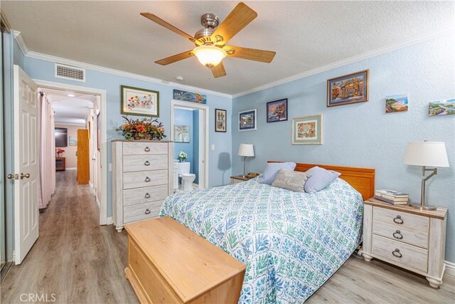 bedroom featuring ceiling fan, light hardwood / wood-style floors, crown molding, and ensuite bath