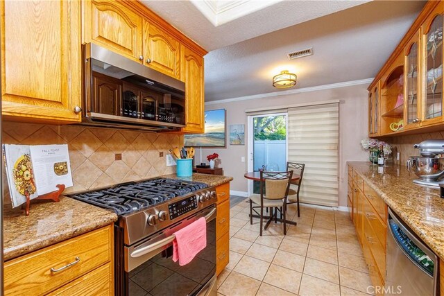 kitchen featuring stainless steel appliances, light stone counters, tasteful backsplash, and light tile patterned flooring