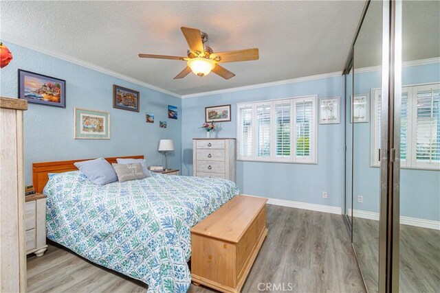 bedroom featuring hardwood / wood-style flooring, ceiling fan, ornamental molding, and multiple windows