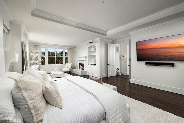 bedroom featuring crown molding, a tray ceiling, and dark wood-type flooring