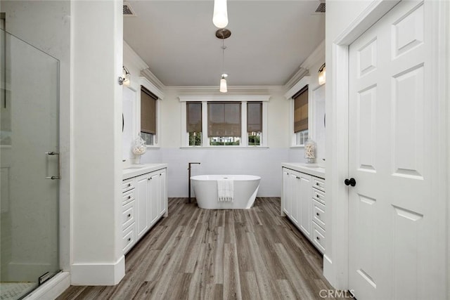 bathroom with independent shower and bath, wood-type flooring, ornamental molding, and vanity