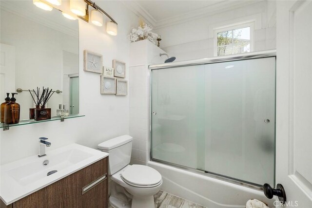 full bathroom featuring ornamental molding, toilet, vanity, and bath / shower combo with glass door