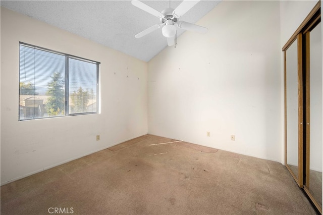 carpeted spare room featuring a textured ceiling, lofted ceiling, and ceiling fan