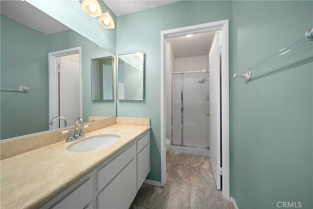 bathroom with a textured ceiling, a shower with door, vanity, and toilet