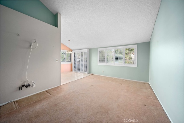 empty room featuring a textured ceiling, lofted ceiling, and carpet floors