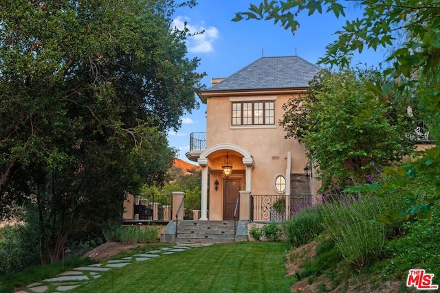 view of front of house featuring a front yard and a balcony