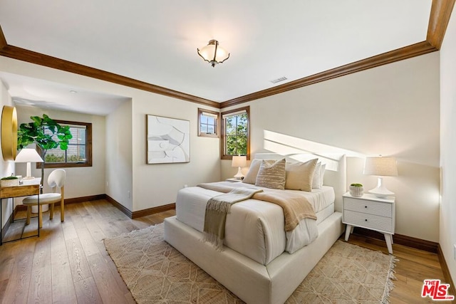 bedroom with light wood-type flooring and crown molding