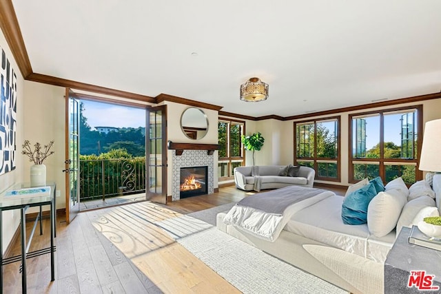 bedroom with hardwood / wood-style flooring, ornamental molding, a fireplace, and access to outside