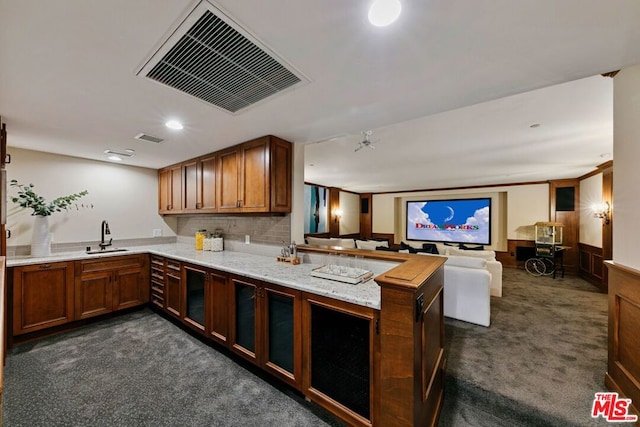 kitchen featuring dark carpet, kitchen peninsula, sink, and tasteful backsplash