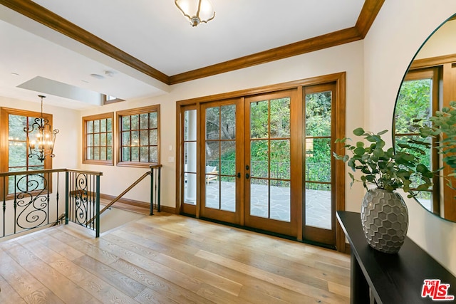 doorway to outside with french doors, light hardwood / wood-style floors, an inviting chandelier, and ornamental molding