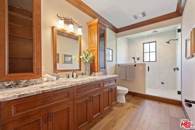 bathroom with vanity, a shower with door, crown molding, hardwood / wood-style floors, and toilet