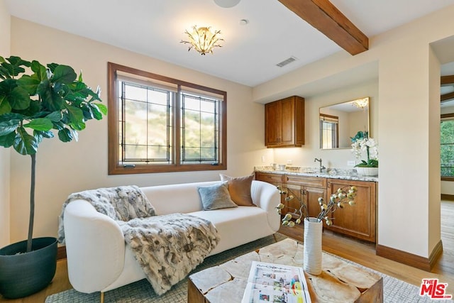 living room featuring beamed ceiling, sink, and light hardwood / wood-style flooring