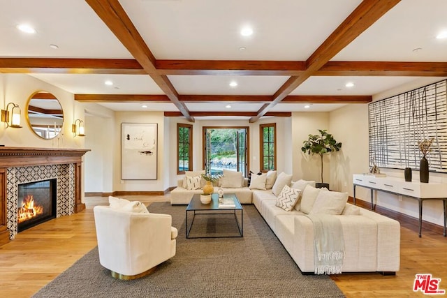 living room with beam ceiling, a tile fireplace, light hardwood / wood-style floors, and coffered ceiling