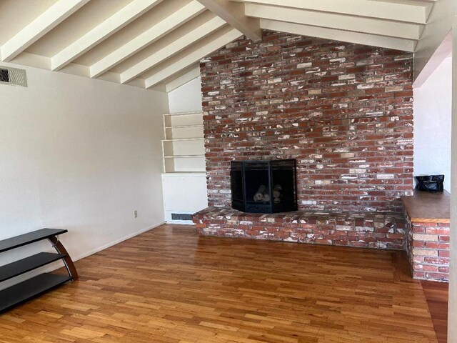 unfurnished living room featuring lofted ceiling with beams, a fireplace, and hardwood / wood-style floors