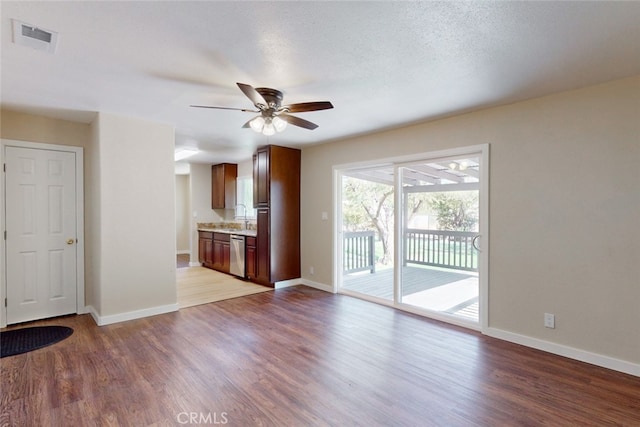 unfurnished living room with ceiling fan, a textured ceiling, and light hardwood / wood-style flooring