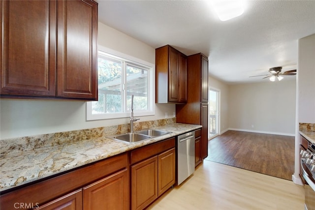 kitchen with ceiling fan, light stone counters, sink, stainless steel dishwasher, and light wood-type flooring