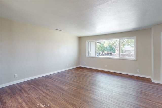 spare room featuring dark hardwood / wood-style floors and a textured ceiling