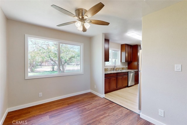 kitchen with light wood-type flooring, sink, stainless steel dishwasher, and ceiling fan