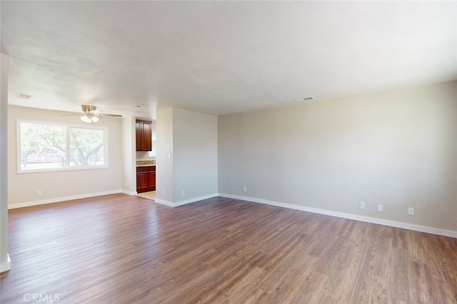 unfurnished living room with a textured ceiling, ceiling fan, and dark hardwood / wood-style flooring