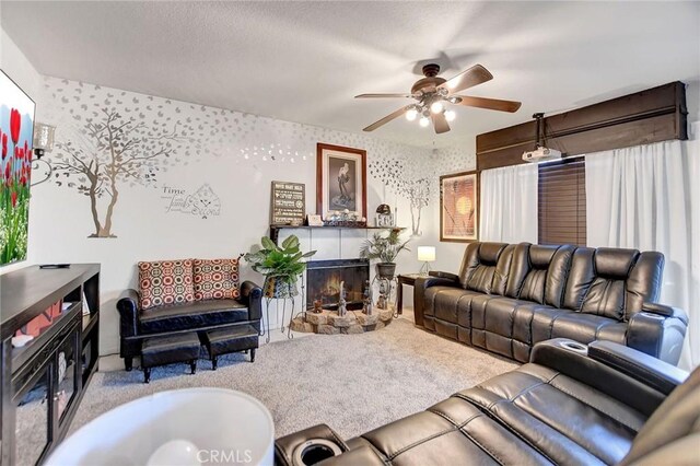 carpeted living room featuring ceiling fan and a stone fireplace