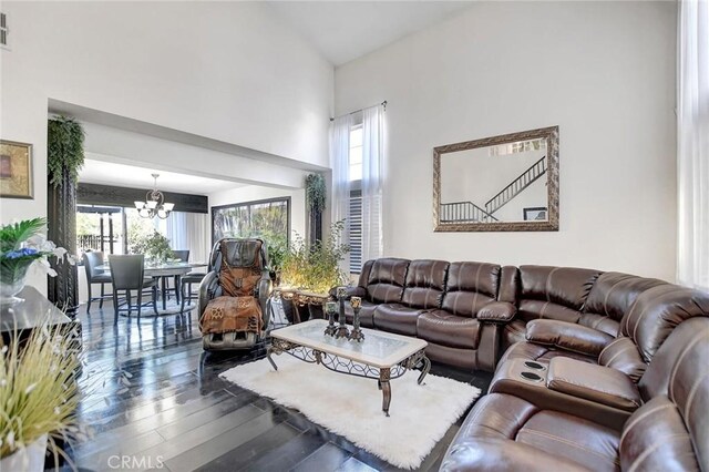 living room with a chandelier, plenty of natural light, high vaulted ceiling, and wood-type flooring