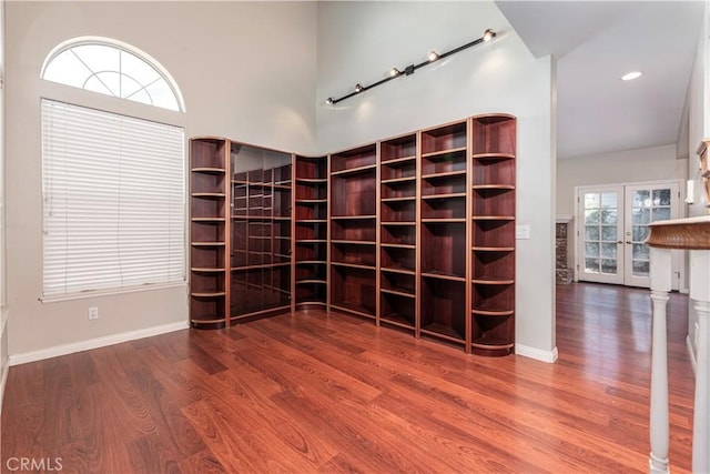 interior space with french doors, rail lighting, a high ceiling, and hardwood / wood-style flooring