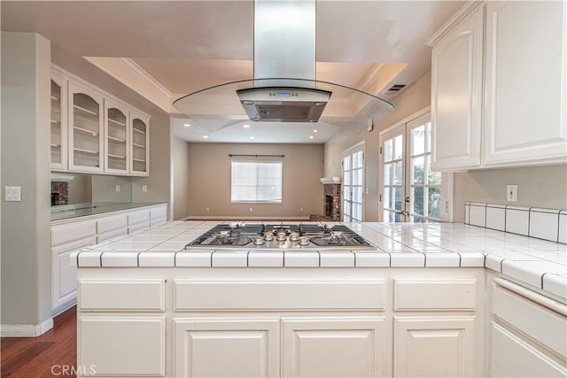 kitchen with kitchen peninsula, stainless steel gas cooktop, tile counters, and a healthy amount of sunlight