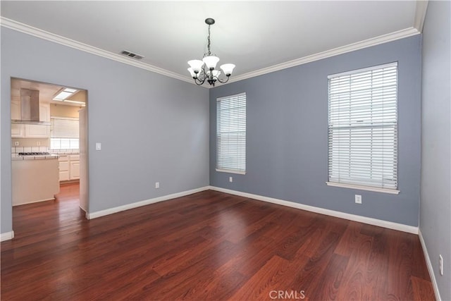 empty room featuring ornamental molding, dark wood-type flooring, and a chandelier