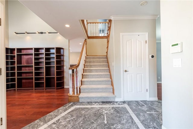 stairs featuring wood-type flooring and crown molding