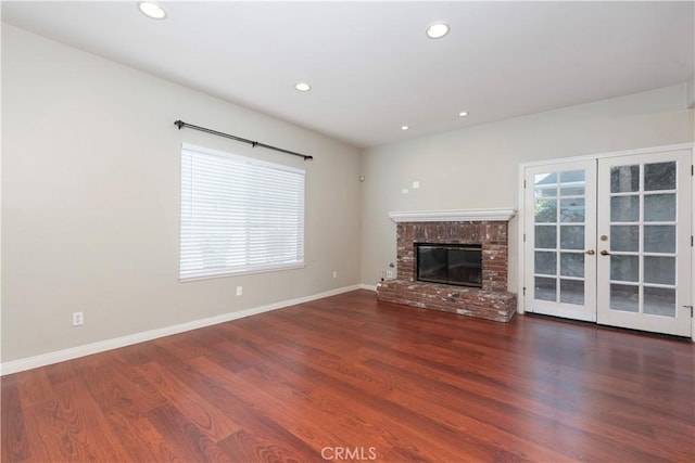 unfurnished living room with a fireplace, french doors, plenty of natural light, and dark wood-type flooring