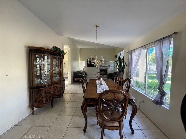 tiled dining area with a notable chandelier, a healthy amount of sunlight, and vaulted ceiling