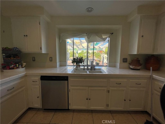 kitchen with tile counters, dishwasher, white cabinets, and sink