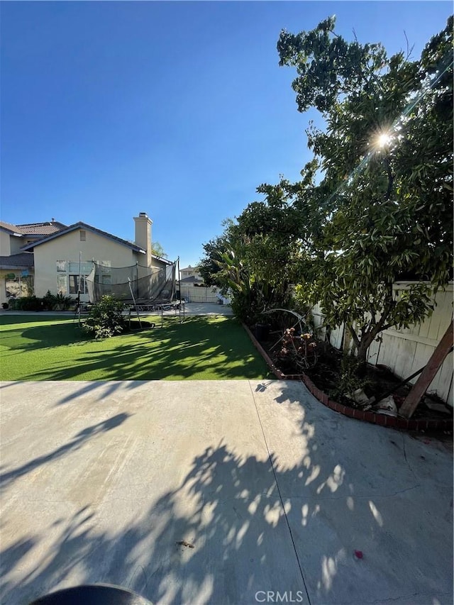 view of property exterior with a yard, a trampoline, and a patio area