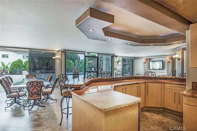 kitchen with light brown cabinets, a raised ceiling, and floor to ceiling windows