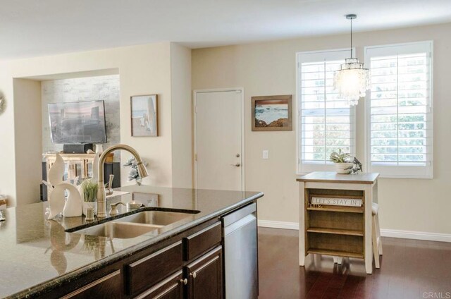 kitchen featuring pendant lighting, light stone counters, dark wood-type flooring, sink, and stainless steel dishwasher