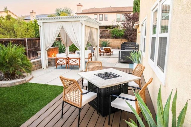 deck at dusk featuring a patio, a pergola, and an outdoor fire pit