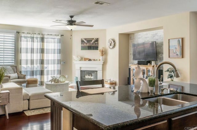 kitchen featuring dark stone counters, sink, dark wood-type flooring, and ceiling fan