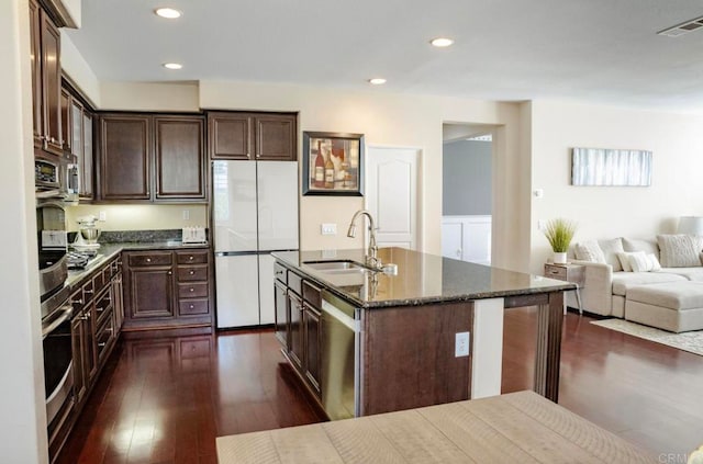 kitchen featuring appliances with stainless steel finishes, dark wood-type flooring, dark brown cabinetry, a center island with sink, and sink